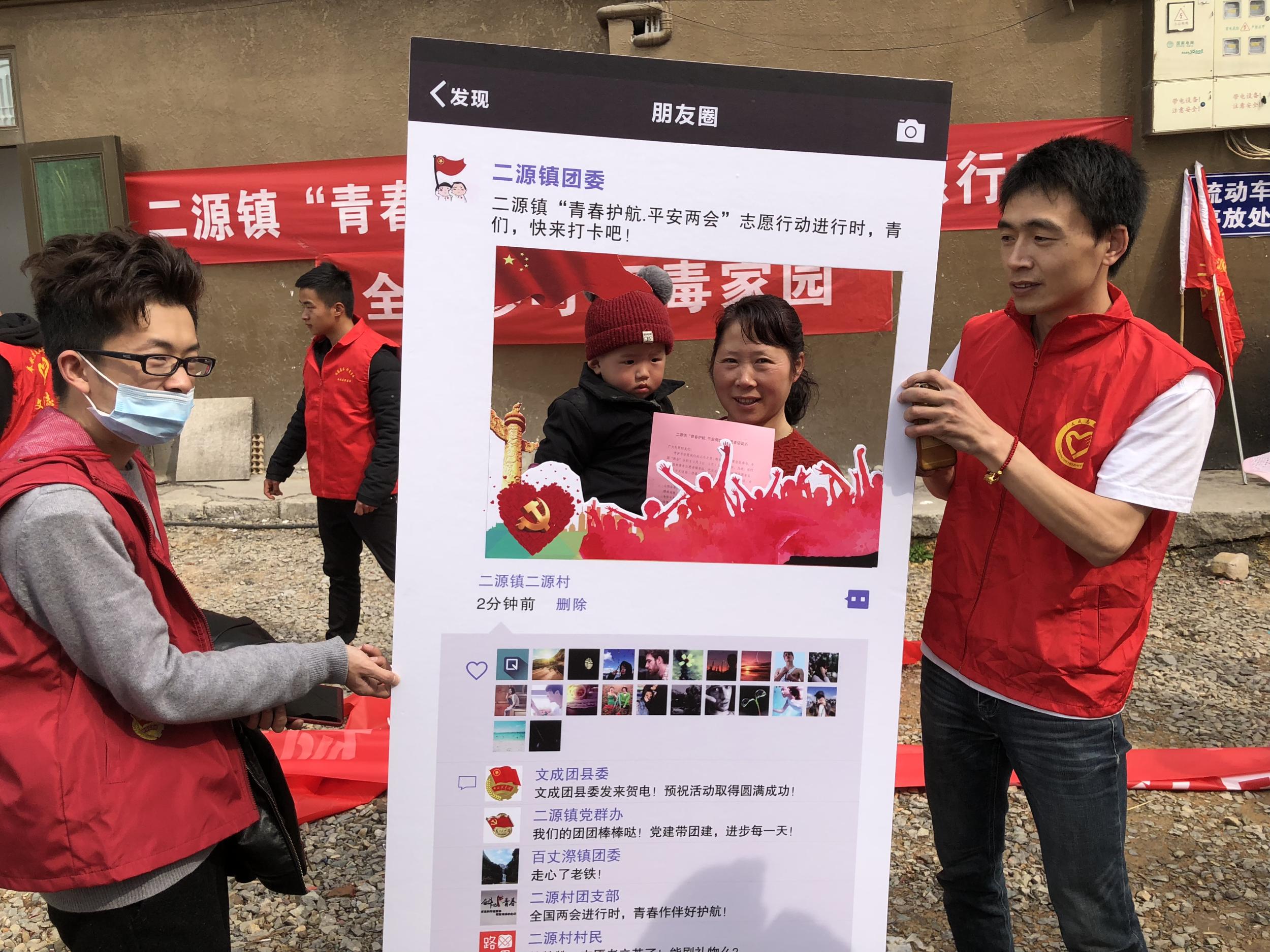 一些围观群众饶有兴致地在趣味拍照kt板前合影留念.
